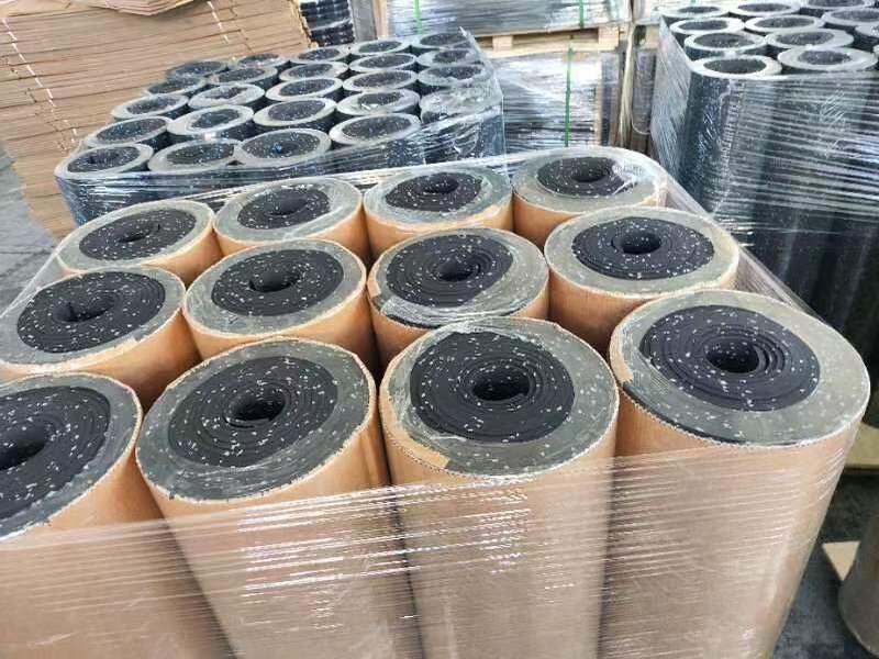 Une usine montrant de grands rouleaux de revêtements de sol en caoutchouc prêts à être expédiés.